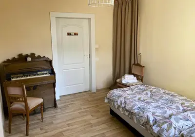 a bedroom with a piano and a bed and a chair at Authentic old studio house in Kaunas