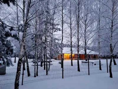 a fence covered in snow with trees and a building at Miško Santorija in Ažuluokesa