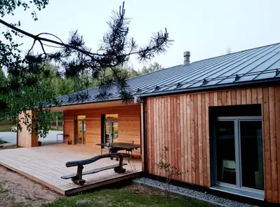 a wooden cabin with a picnic table on a deck at Miško Santorija in Ažuluokesa