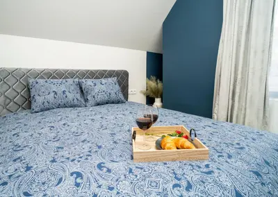 a tray of fruit and a glass of wine on a bed at Fort63 Studio in Kaunas