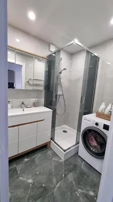 a bathroom with a shower and a washing machine at New apartment in the city in Šiauliai