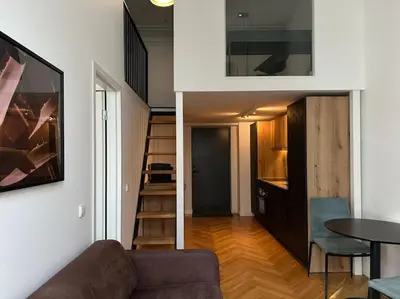 a living room with a couch and a table and a staircase at M Loft3 in Kaunas