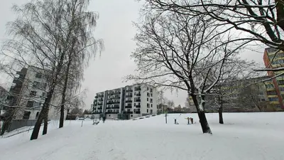 a park covered in snow with buildings and trees at Kavoliuko 14 in Vilnius