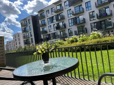 a glass table with a vase of flowers on a balcony at Near Ozas in Vilnius