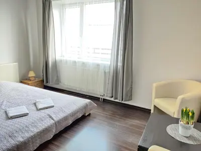 a bedroom with a bed and a chair and a window at Apartments near BIG in Vilnius