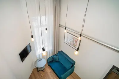 a room with a blue chair and a television at Teeny Tiny Lofts in Center in Kaunas