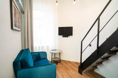 a living room with a blue chair and a staircase at Teeny Tiny Lofts in Center in Kaunas
