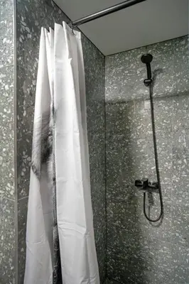 a shower with a white shower curtain in a bathroom at Teeny Tiny Lofts in Center in Kaunas