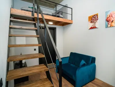 a living room with a spiral staircase and a blue chair at Teeny Tiny Lofts in Center in Kaunas