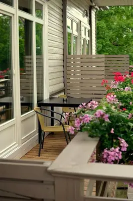 a porch with a table and flowers on it at The House in Druskininkai