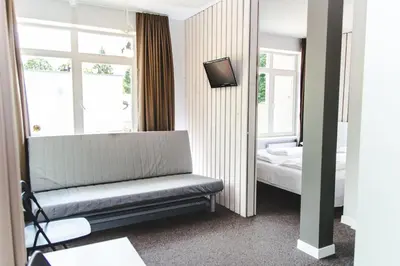a room with a bench and a bed and windows at The House in Druskininkai