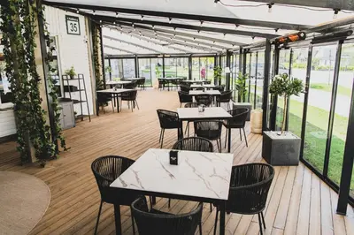 a restaurant with tables and chairs and windows at The House in Druskininkai