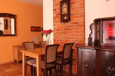 a dining room with a table and chairs and a clock at Jauku Erdvu Šilta in Kaunas