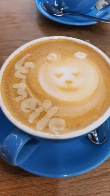 a cup of cappuccino with a face drawn on it at Violetinis namelis/ Sodyba Geras in Anykščiai
