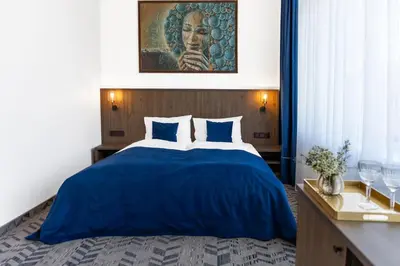 a bedroom with a bed with a blue comforter at AN Hotel self check-in in Šiauliai