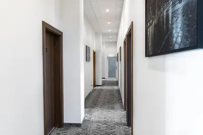 a corridor with white walls and a hallway with black doors at AN Hotel self check-in in Šiauliai