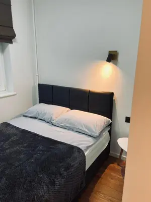 a bed with a black headboard in a room at Sun Clock Apartment in Šiauliai