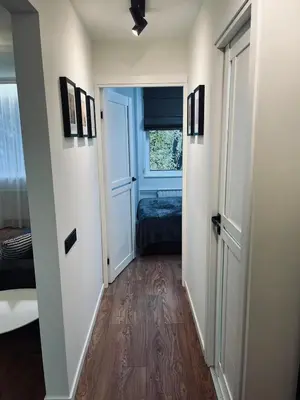 a hallway with a room with a bed and a window at Sun Clock Apartment in Šiauliai