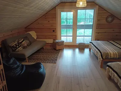 a attic room with a couch and a bed and a window at Sodyba vienkiemyje 