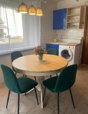 a kitchen with a table with green chairs and a table with flowers at 2 bedroom apartment close to Kaunas airport in Karmelava in Karmėlava