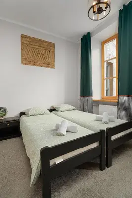 two beds in a bedroom with green curtains at Church through the window in Vilnius