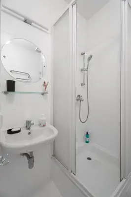 a white bathroom with a sink and a shower at Church through the window in Vilnius