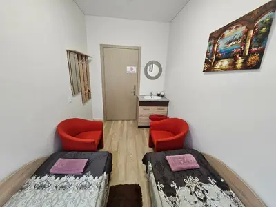 a room with two beds and two red chairs at Kauno Apartamentai in Kaunas