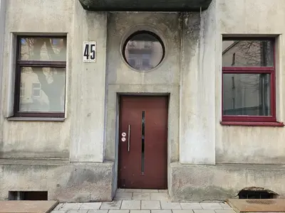 a building with a red door and two windows at Kauno Apartamentai in Kaunas