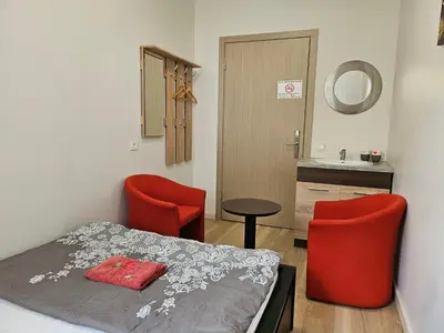 a bedroom with a bed and two red chairs at Kauno apartamentai Big bed in Kaunas