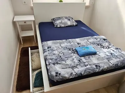 a small bedroom with a bed with a blue comforter at Kauno apartamentai big bed in Kaunas