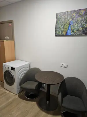 a room with a table and two chairs and a washing machine at Kauno apartamentai big bed in Kaunas
