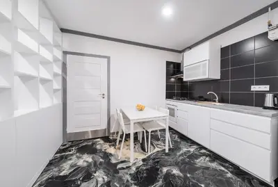 a kitchen with white cabinets and a white table at Klaipedos Apartment - Lollo Stay in Vilnius