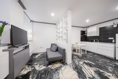 a living room with a couch and a tv and a kitchen at Klaipedos Apartment - Lollo Stay in Vilnius