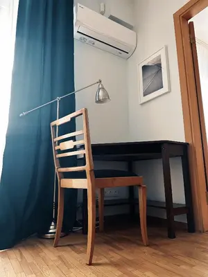 a chair sitting in front of a desk with a lamp at City Center Apartments in Vilnius