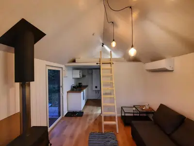 a room with a couch and a ladder in a tiny house at Ramybės parkas in Sponėnai