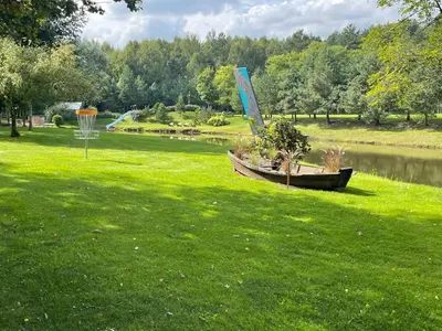 a boat sitting in the grass next to a pond at Ramybės parkas in Sponėnai
