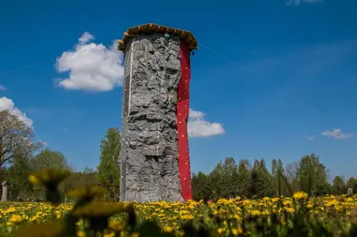 a stone monument in a field of flowers at Ramybės parkas in Sponėnai