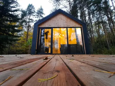 a house in the woods with a wooden floor at Ramybės parkas in Sponėnai