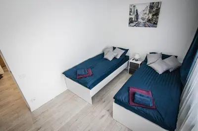 a bedroom with two beds with blue sheets at Ramūs apartamentai in Anykščiai