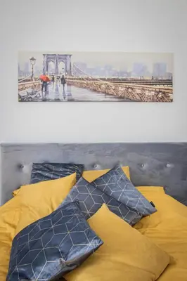 a bed with yellow and blue pillows and a bridge at Ramūs apartamentai in Anykščiai