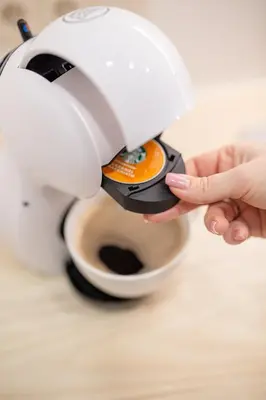 a person holding a coffee maker on top of a cup at Lukiskes square apartment (Oldtown) in Vilnius