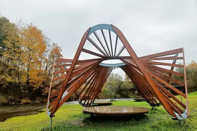 a large wooden structure in a grass field at River Vilnele View Studio in Vilnius