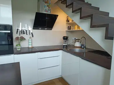 a kitchen with white cabinets and a sink and stairs at River Vilnele View Studio in Vilnius