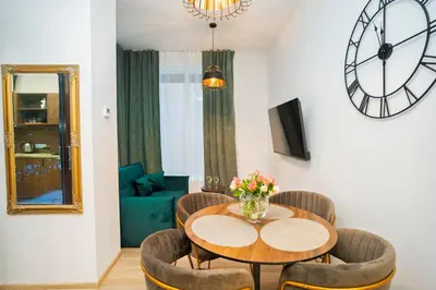 a dining room with a table and chairs and a clock at Central Station Apartment No1 in Kaunas