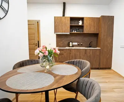 a table and chairs with a vase of flowers on it at Central Station Apartment No1 in Kaunas