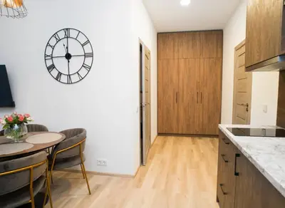 a kitchen with a table and a clock on the wall at Central Station Apartment No1 in Kaunas