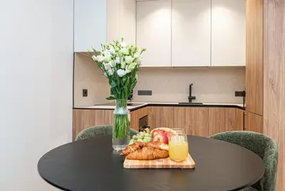 a table with a vase of flowers and a plate of food at #stayhere - New & Stylish Minimalistic 1BDR Vilnius City Center in Vilnius