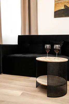two wine glasses on a table in front of a couch at Central Station Apartment No2 in Kaunas