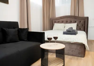 a bedroom with a bed and a couch and two glasses of wine at Central Station Apartment No2 in Kaunas