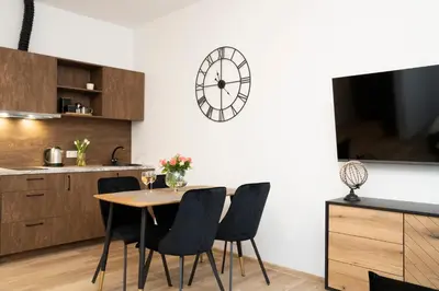 a dining room with a table and chairs and a clock at Central Station Apartment No2 in Kaunas